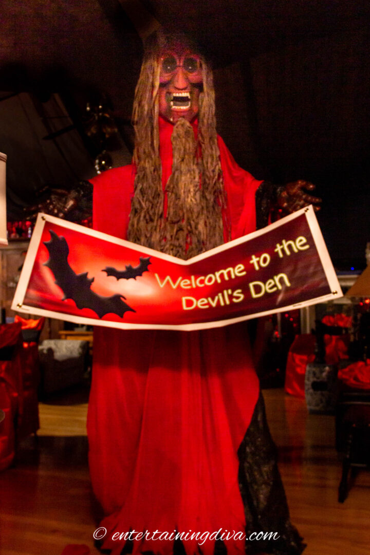 red devil hanging from the ceiling with a welcome sign in his hands