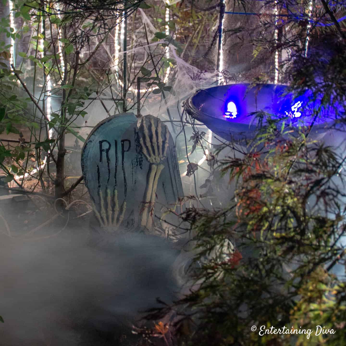 Fog swirling around a Halloween grave stone and fountain