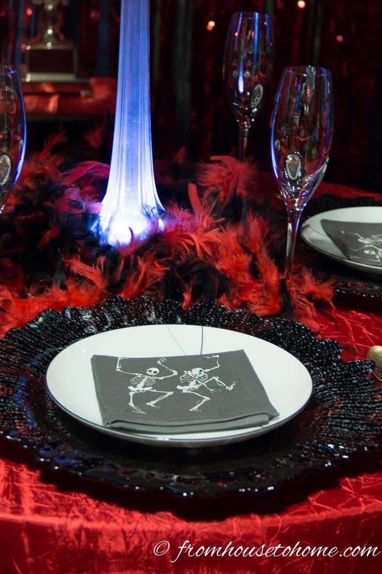 Fallen angel and devil place setting with white plates on black chargers and a red table cloth