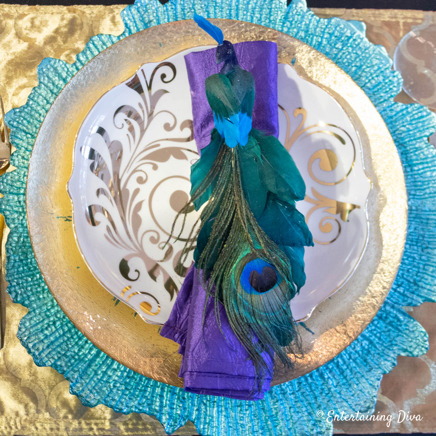 Peacock place setting with purple napkin, turquoise charger and gold plate