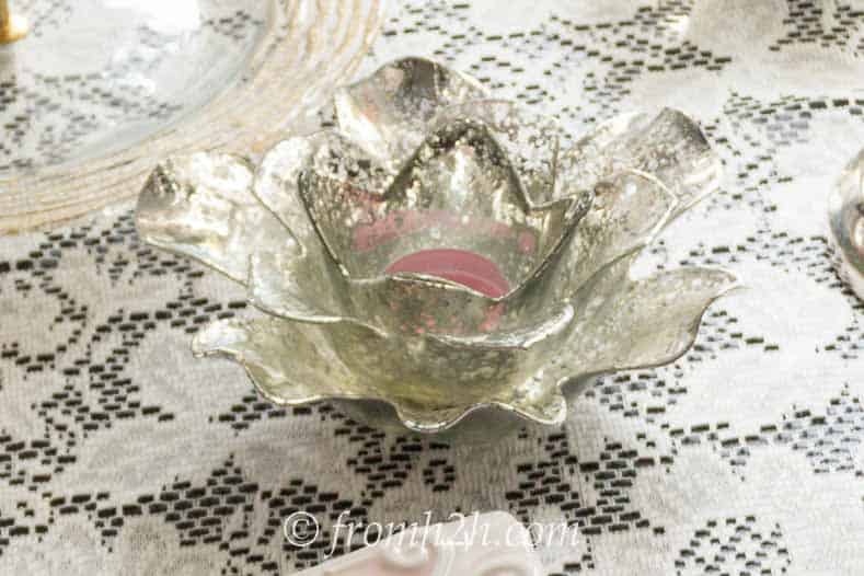Rose-shaped mercury glass candle holder on a lace tablecloth