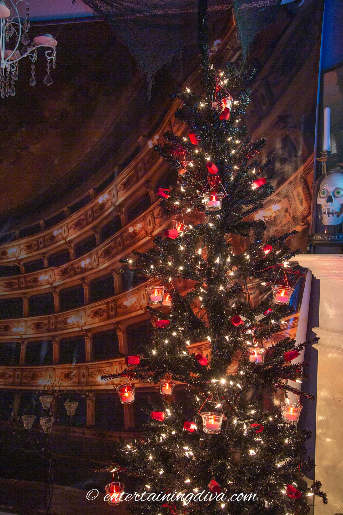 A black Christmas tree decorated with red tealight candles and faux red roses for a Phantom of the Opera party