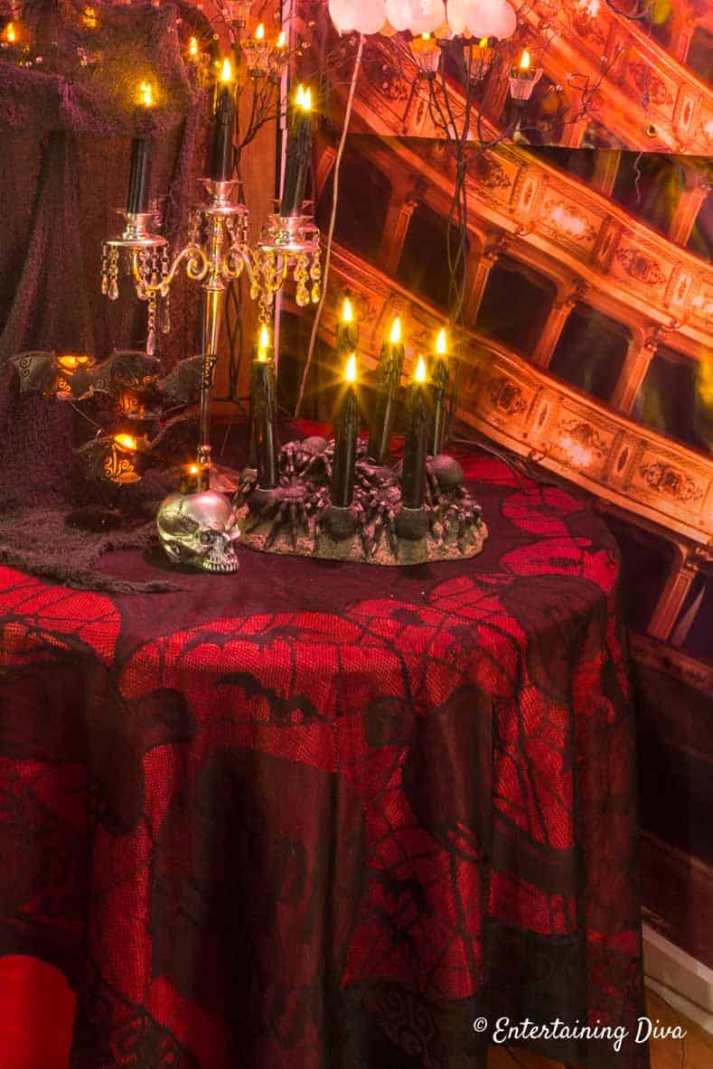 Black spider web lace over red table cloth on a table with Halloween candles