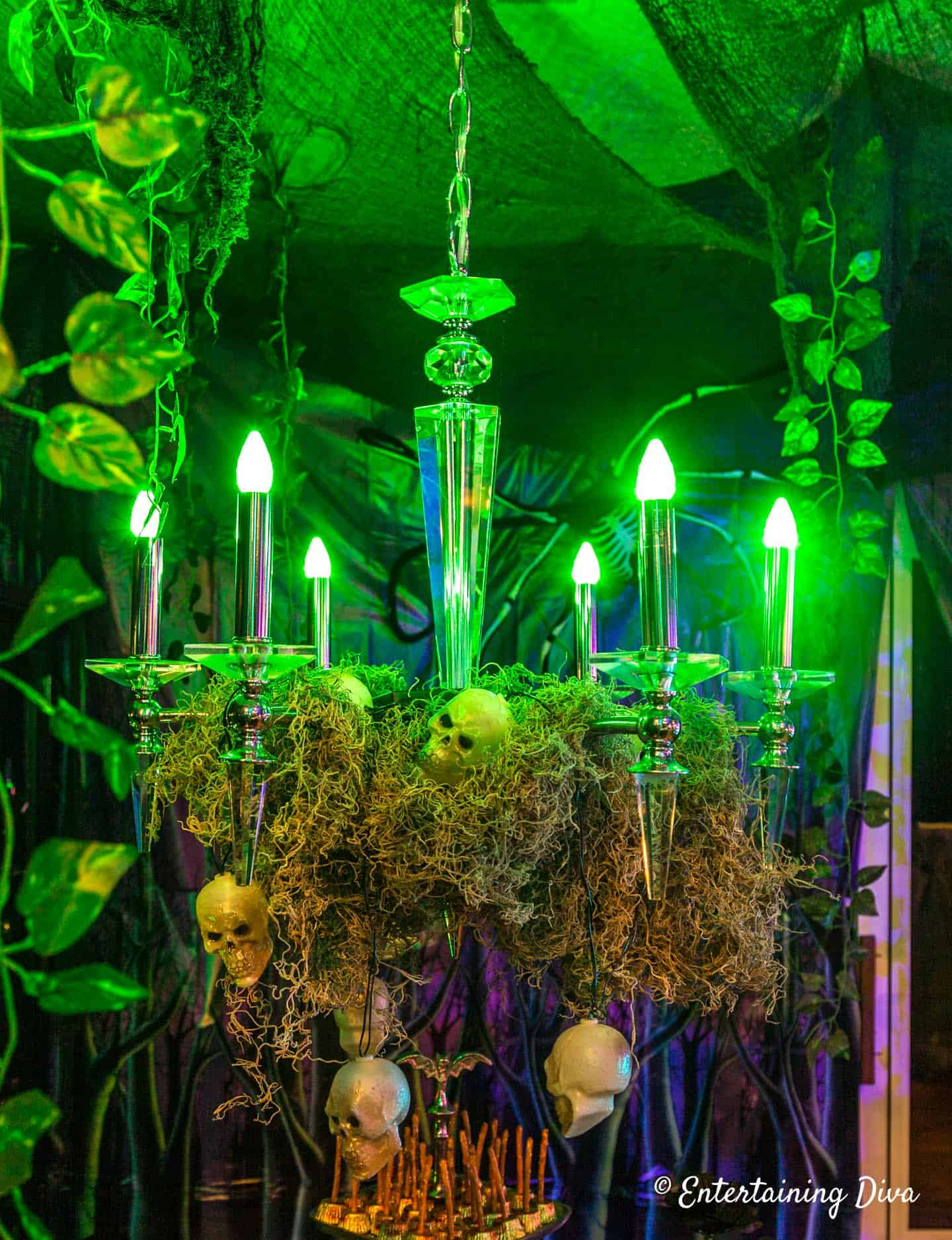 Chandelier with green lightbulbs, moss and small skeleton heads in a haunted house