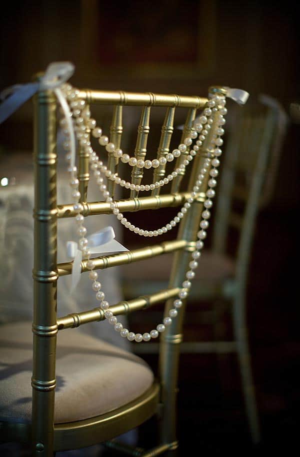 Gold bamboo chairs with white string of pearls on the back from lovemydress.net