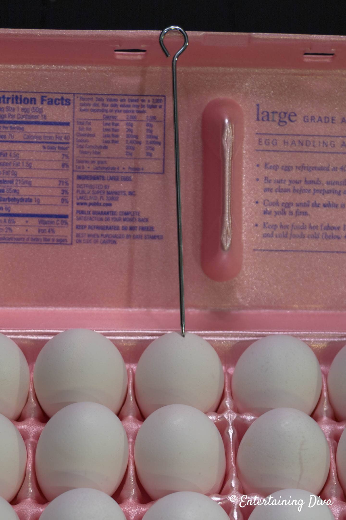A craton of eggs with a metal skewer