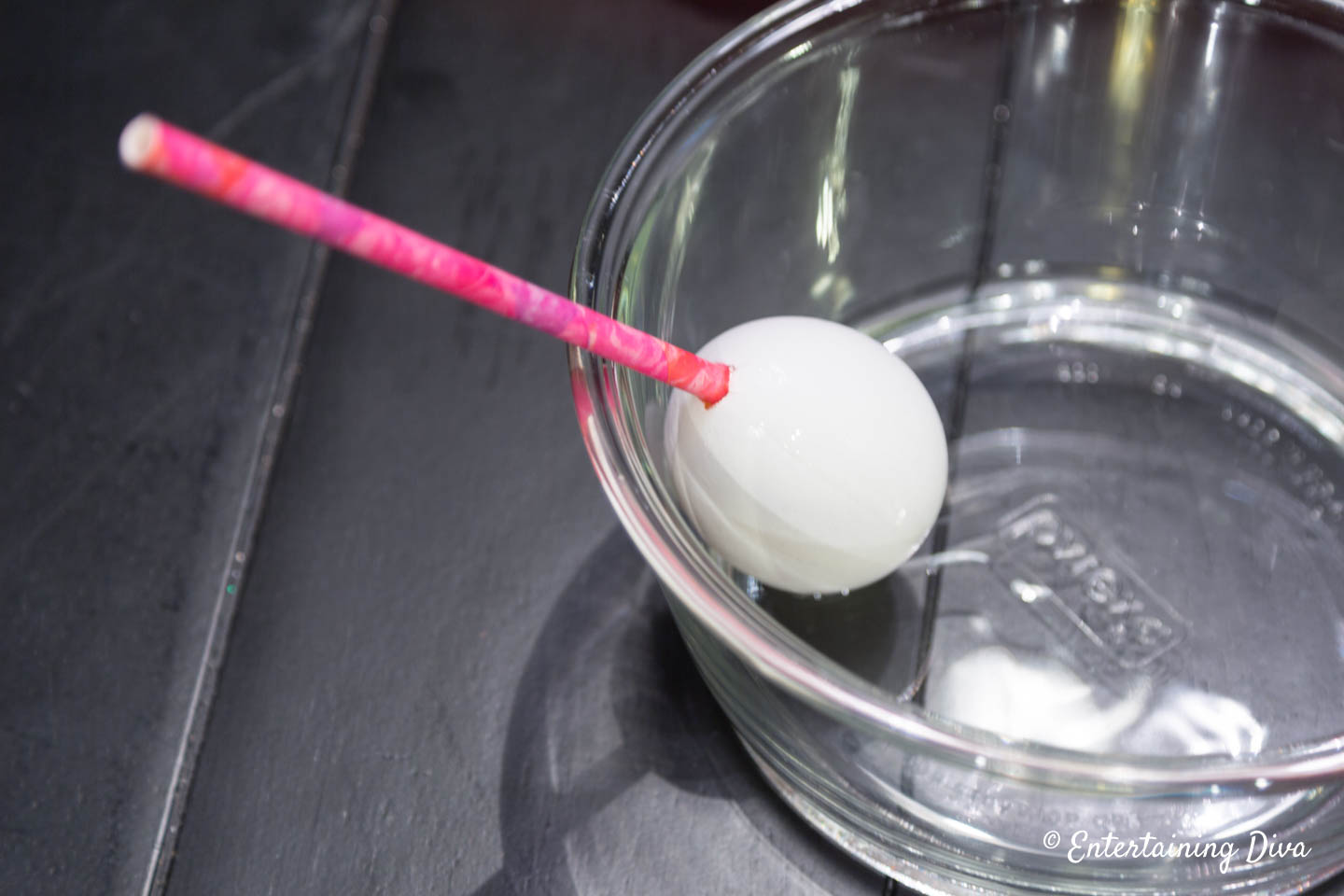 A straw in a hole in one end of an egg
