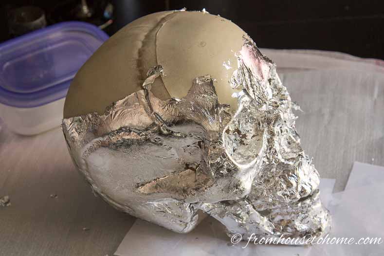 The side view of the skull half covered with silver leaf