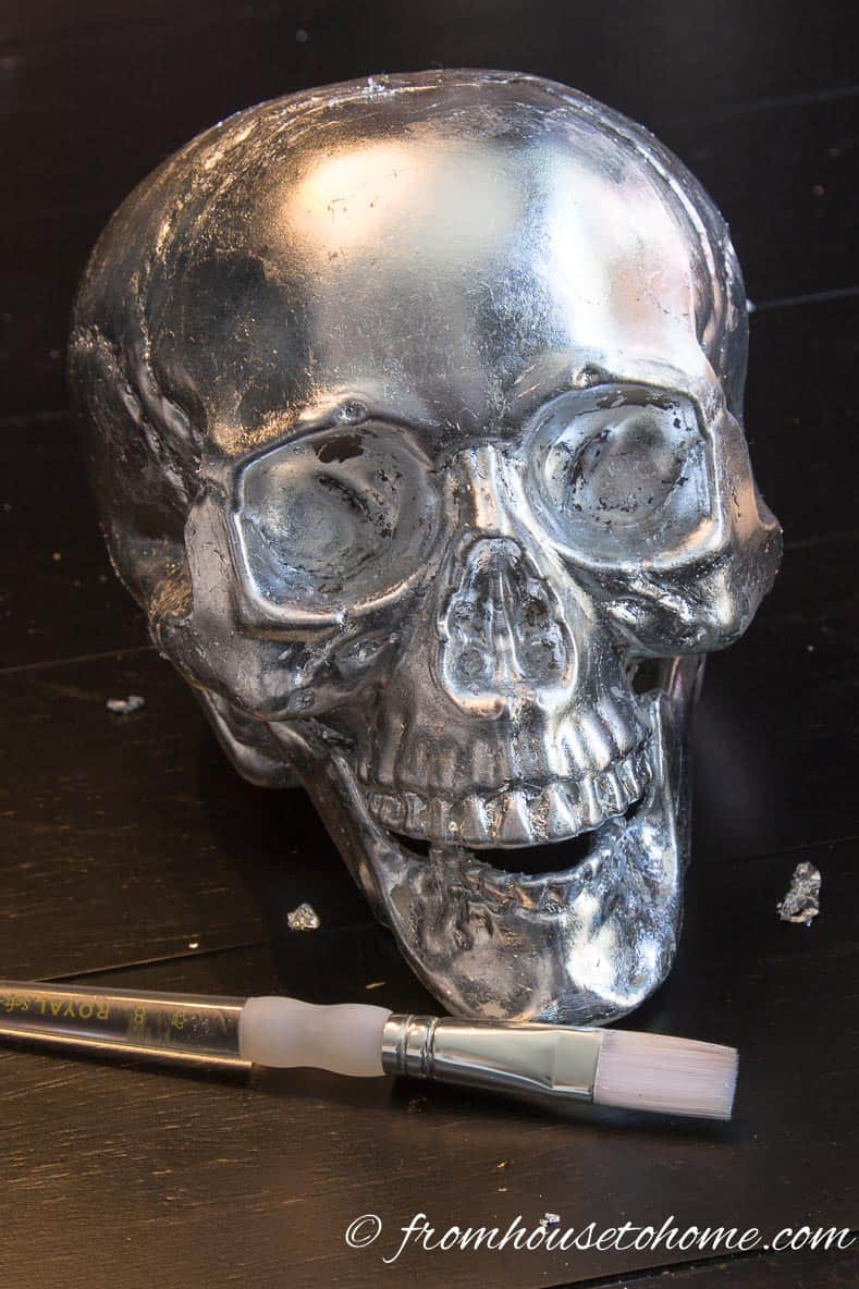 A silver leaf skull with a small artist brush in front of it