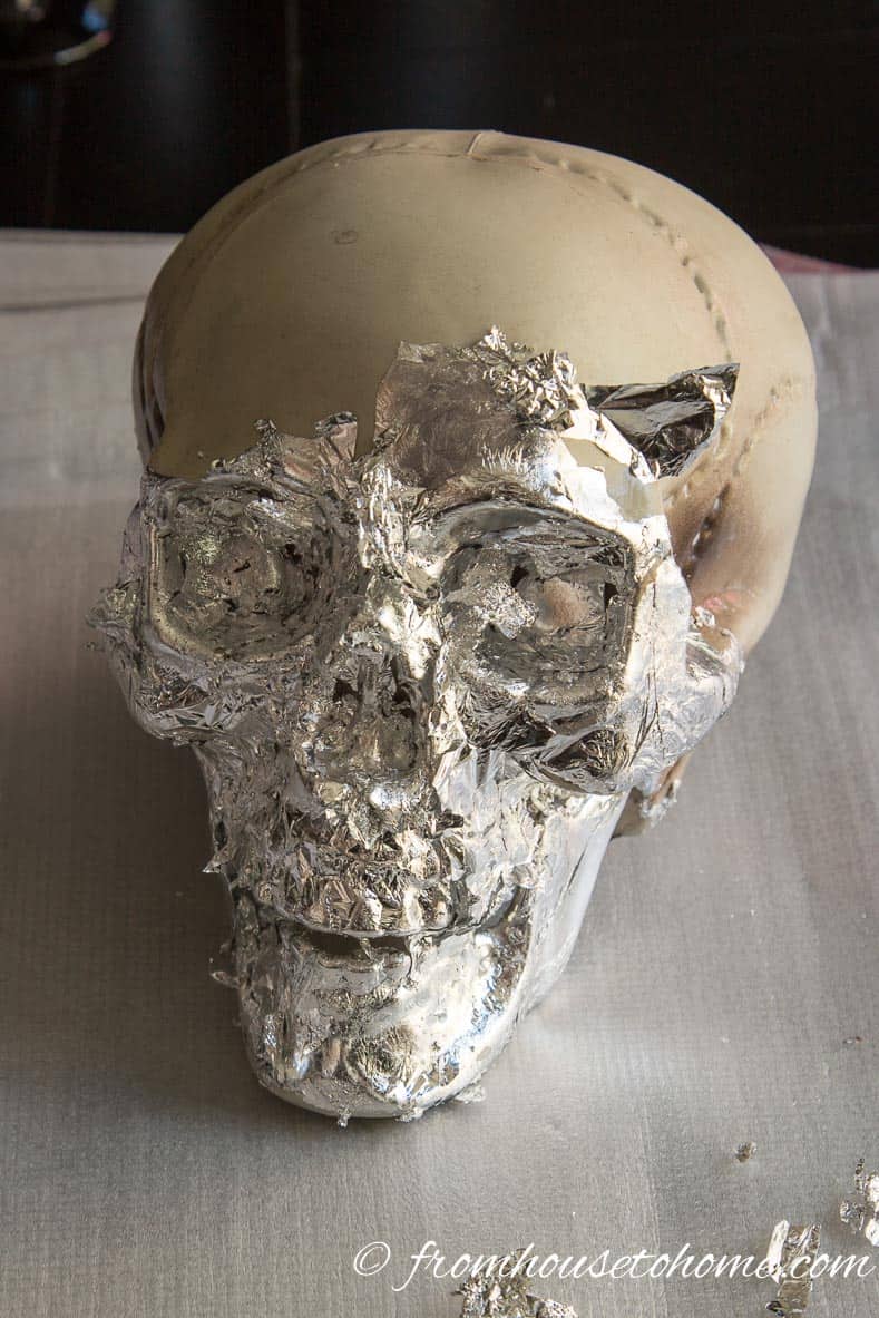 Skull half covered with silver leaf with bits sticking out