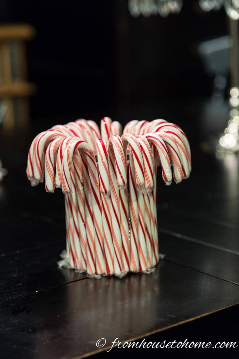 Keep adding candy canes until they completely surround the can | Add some holiday spirit to your Christmas table decor with this red and white DIY candy cane Christmas centerpiece! | DIY Quick and Easy Candy Cane Christmas Centerpiece