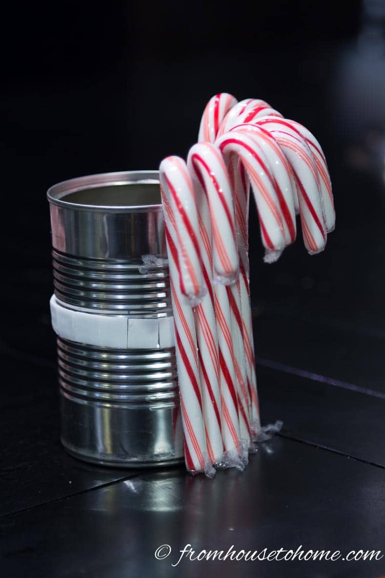Stick the candy canes onto the double sided tape | Add some holiday spirit to your Christmas table decor with this red and white DIY candy cane Christmas centerpiece! | DIY Quick and Easy Candy Cane Christmas Centerpiece