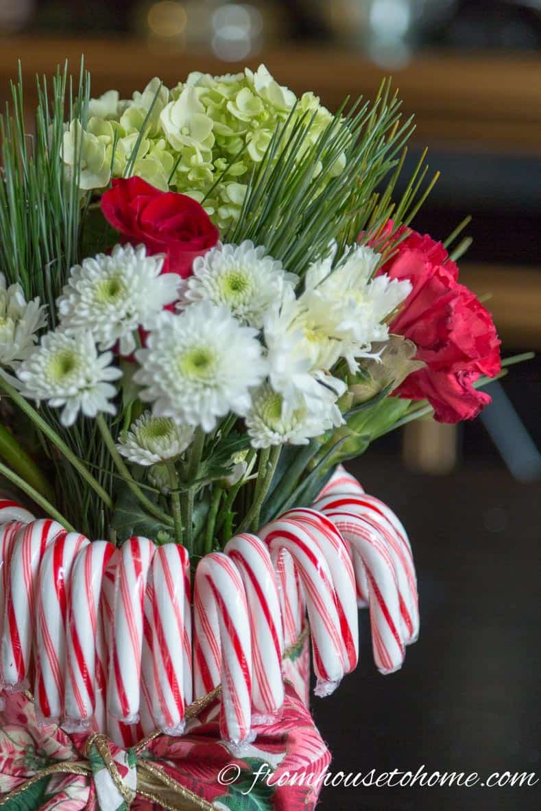 Add the flowers and fill in with the greens | Add some holiday spirit to your Christmas table decor with this red and white DIY candy cane Christmas centerpiece! | DIY Quick and Easy Candy Cane Christmas Centerpiece