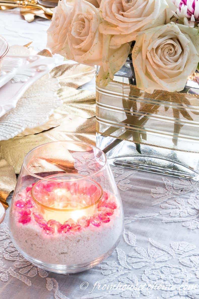 Stemless wineglass filled with white sand, pink crystals and a tealight candle