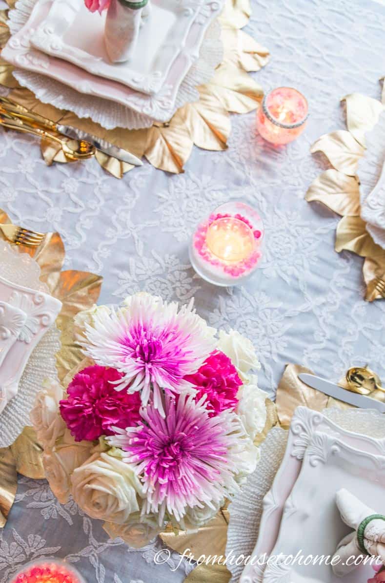 White and pink flowers with white and pink candle on a pink and gold tablescape