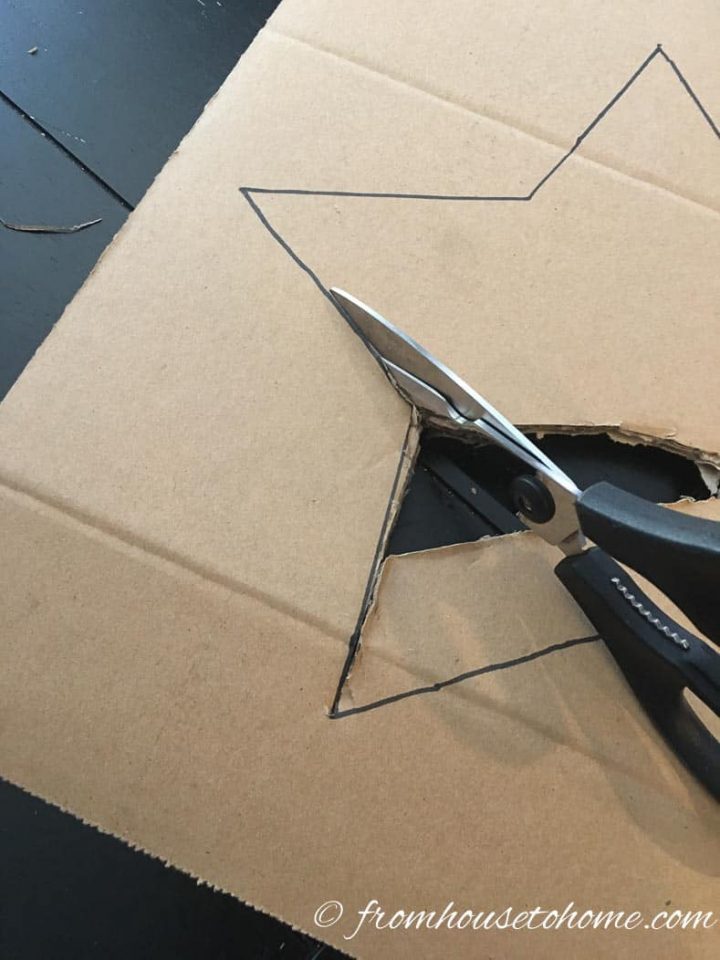 Scissors cutting out a star from a piece of cardboard