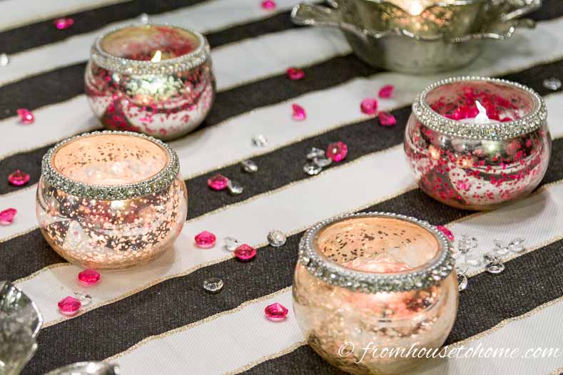 Pink and clear crystals with mercury glass candle holders on a black and white tablecloth