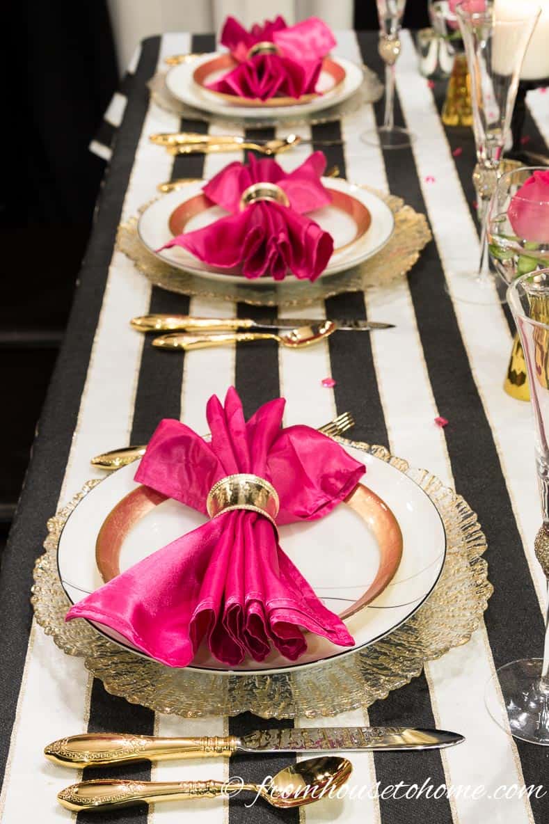 Kate Spade inspired table setting with fuchsia napkins, gold and white place setting and black and white striped tablecloth
