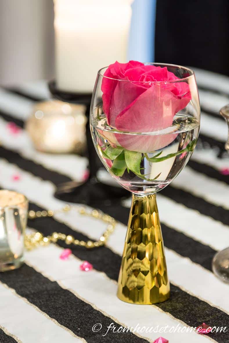 Valentine's Day table decorating idea with a pink rose in a tall wine glass