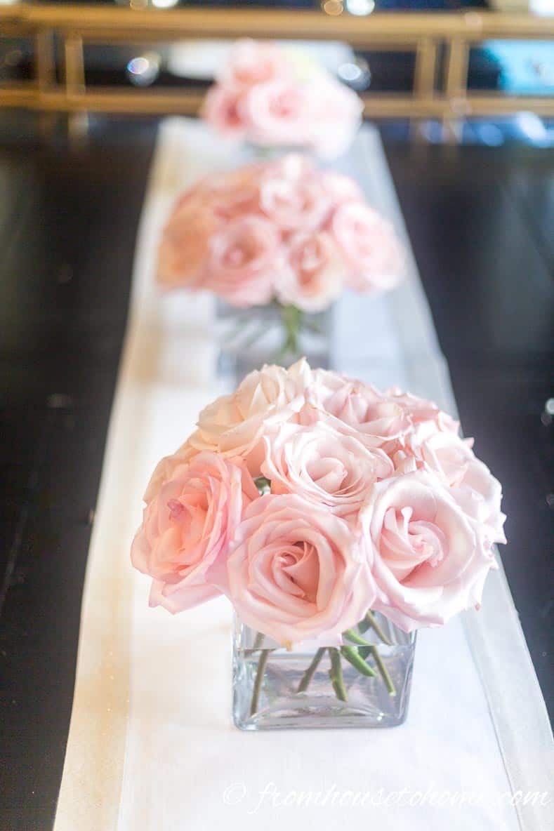 Pink roses in square vases on a table runner