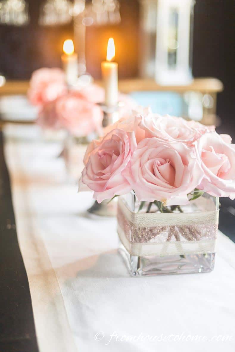 Simple but elegant pink floral centerpiece made with pink roses in square vases repeated down the length of the table