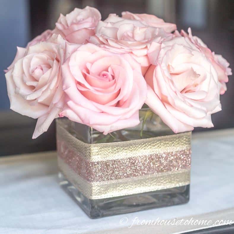 A simple but elegant DIY flower centerpiece made with pink roses in a square vase 