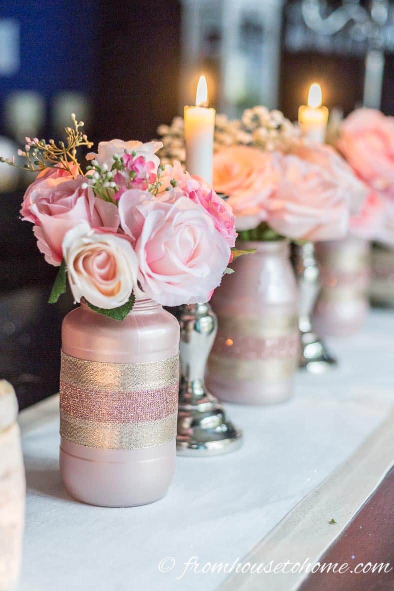 A rose gold centerpiece made with roses and baby's breath in DIY rose gold glass jar vases 