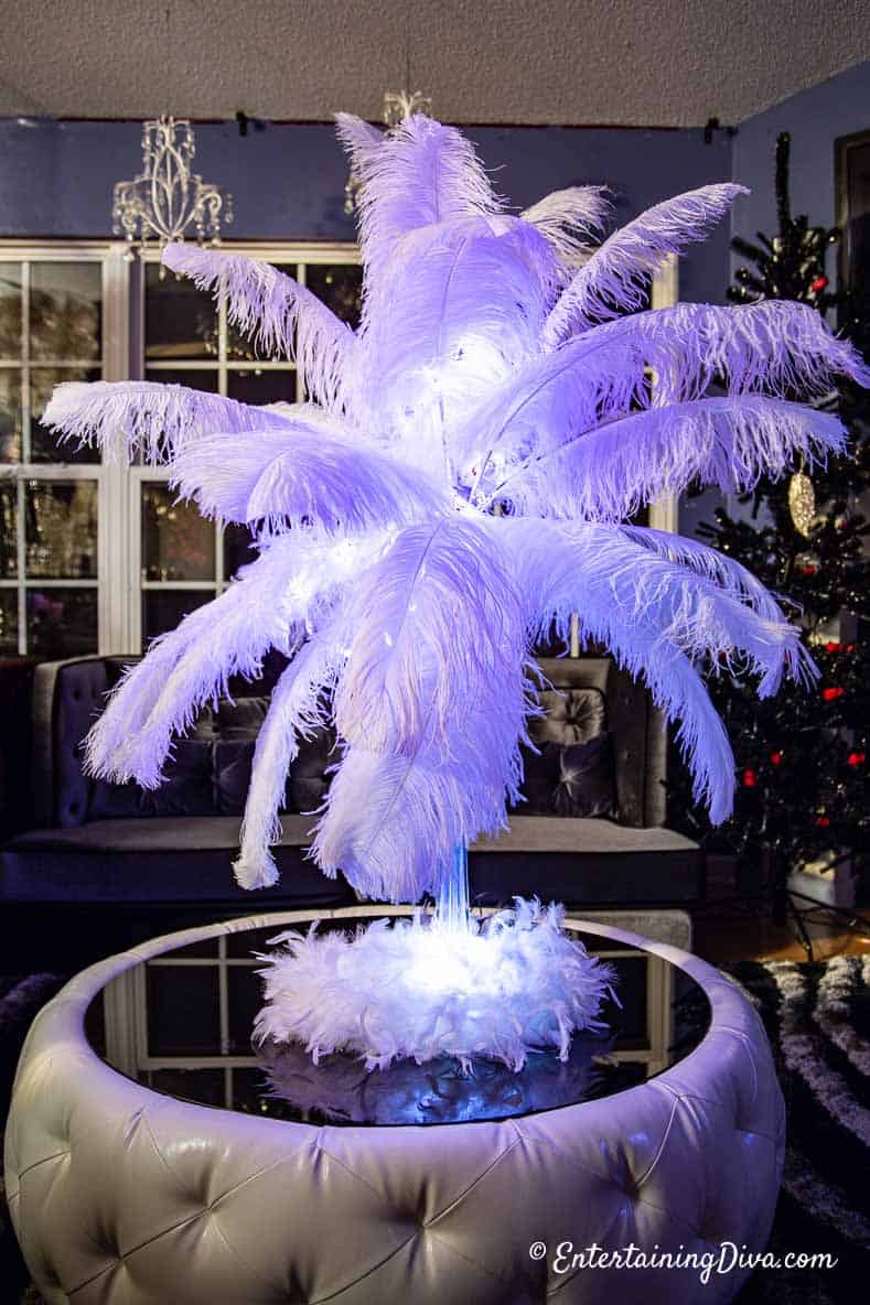 White ostrich feather centerpiece with pink glitter lights in the feathers and a white feather boa around the base