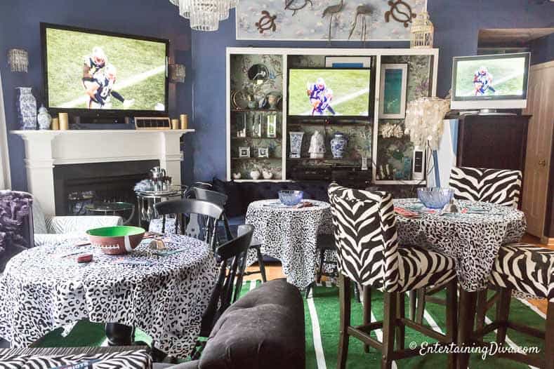living room with multiple TVs, a DIY football field area rug and black and white tablecloths and chairs