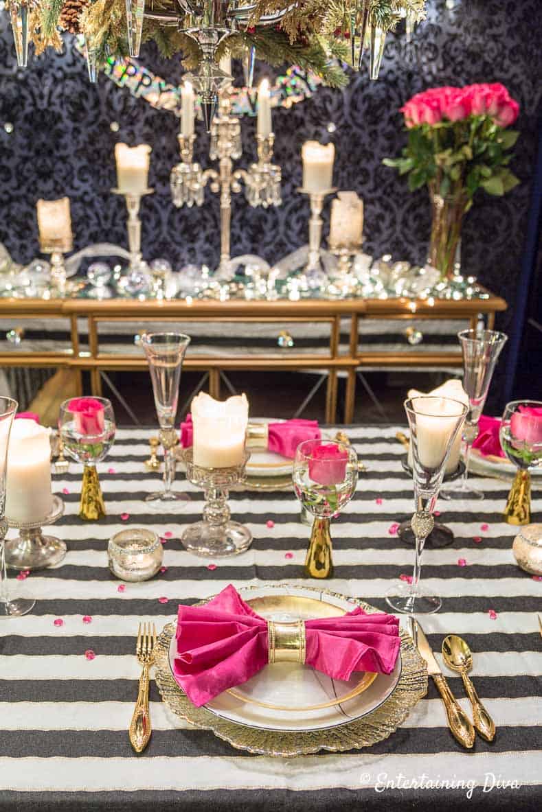kate spade themed party decor ideas tablescape with black and white tablecloth, gold plates and pink accents