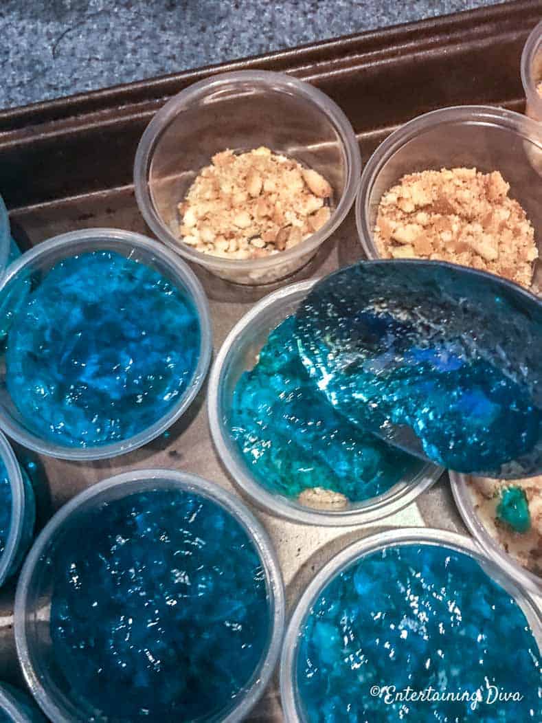 This 'under the sea' Swedish fish jello shot recipe with coconut rum is awesome! It is made with Malibu rum and is one of the best blue jello shots I've tried. #entertainingdiva #jelloshots #cocktailrecipe #summerfun #partyideas Spoon in the berry blue jello shot mixture