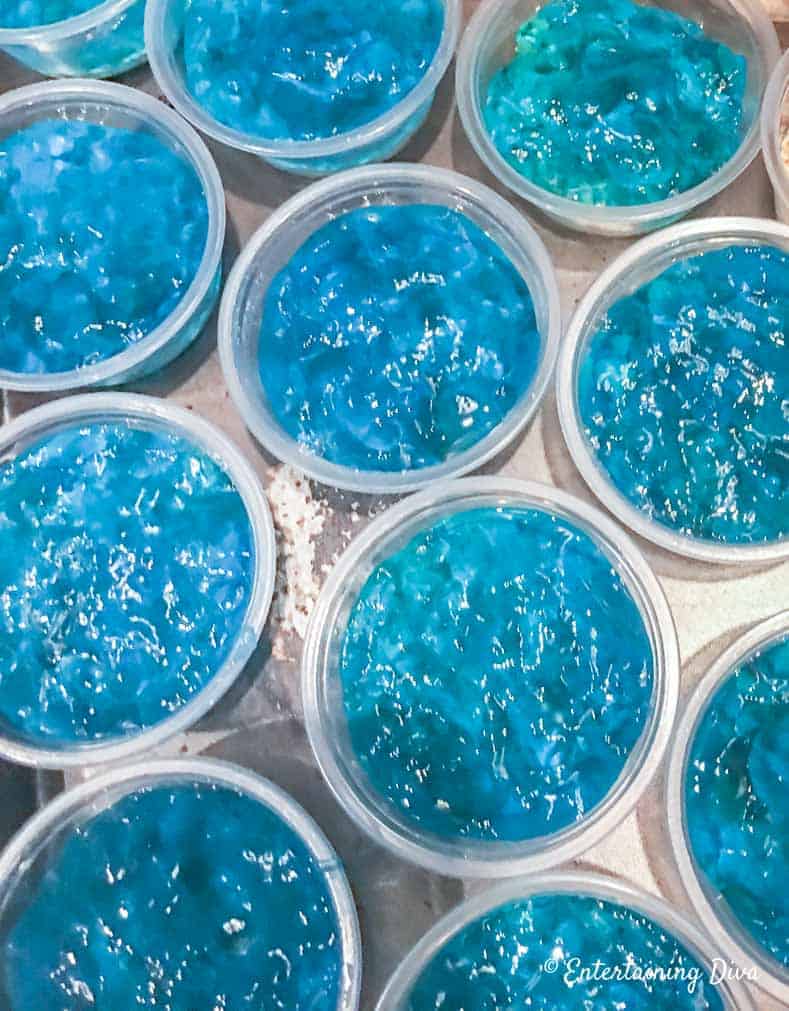This 'under the sea' Swedish fish jello shot recipe with coconut rum is awesome! It is made with Malibu rum and is one of the best blue jello shots I've tried. #entertainingdiva #jelloshots #cocktailrecipe #summerfun #partyideas Wavy berry blue jello mixture in jello shot cups