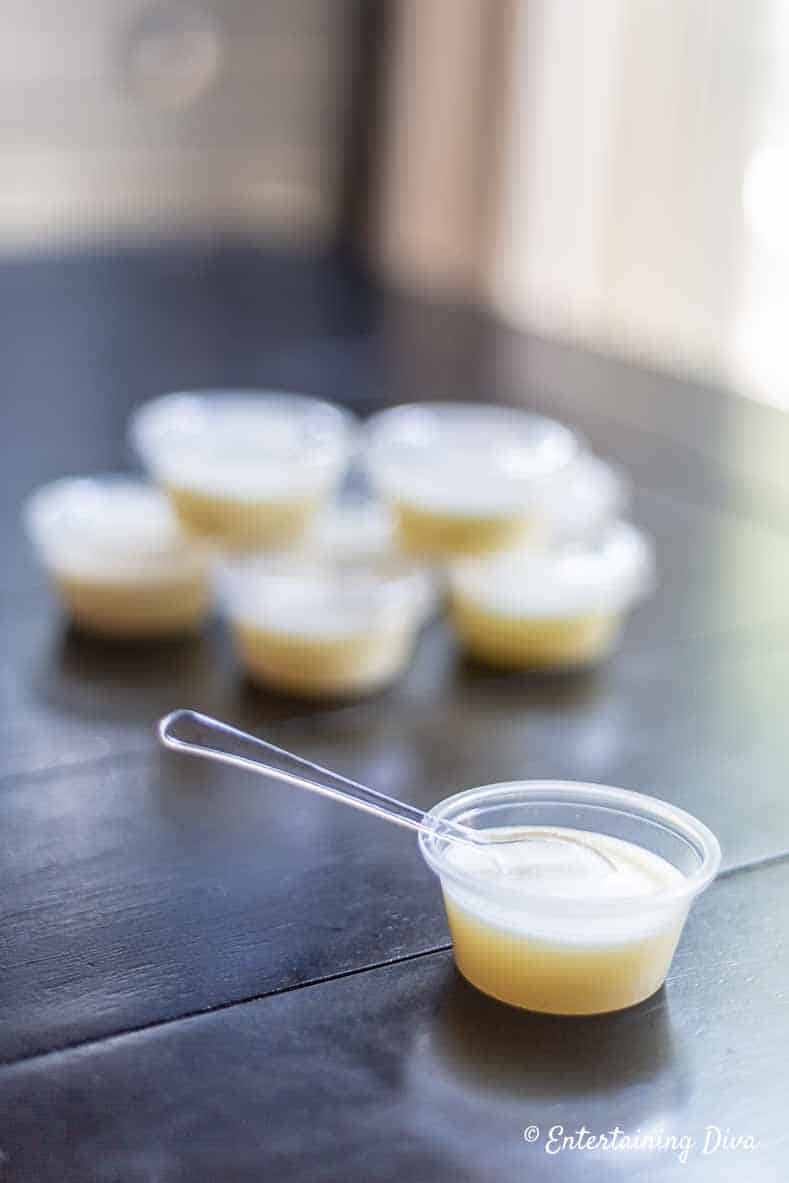 These easy white Pina Colada jello shots are the best! They are made with real pineapple juice, coconut milk and Malibu rum...just like the real drinks. Perfect for summer parties. #EntertainingDiva #summerfun #jelloshots #cocktails #drinks white pina colada gelatin shot with spoon