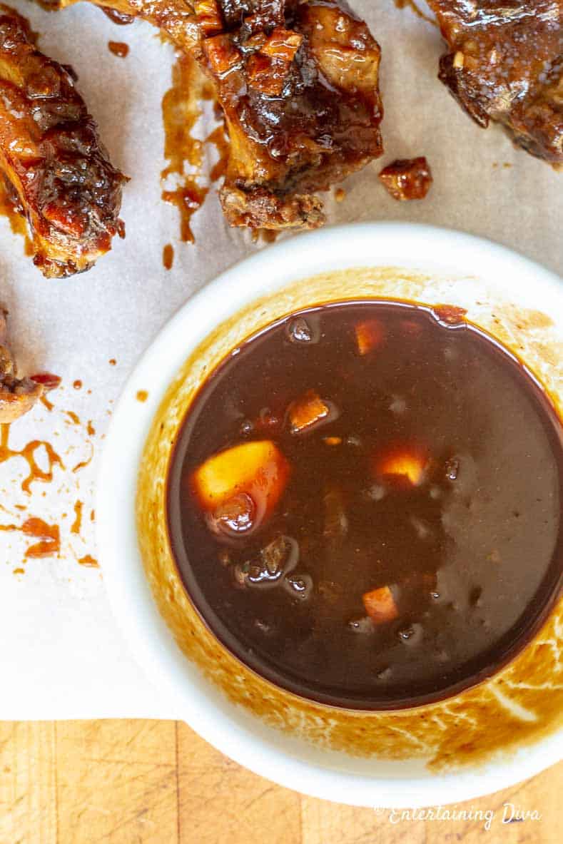 Homemade BBQ sauce in a bowl beside some ribs