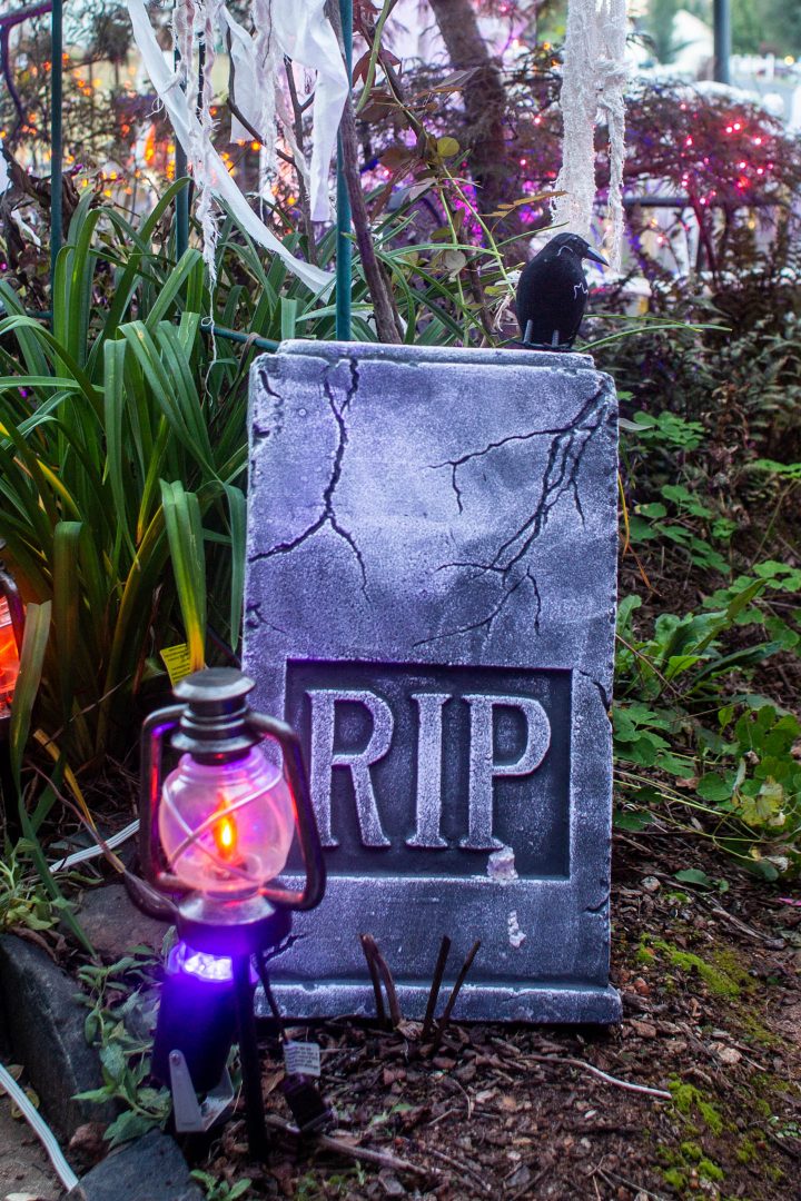 Fake crow sitting on top of a Halloween cemetery tombstone