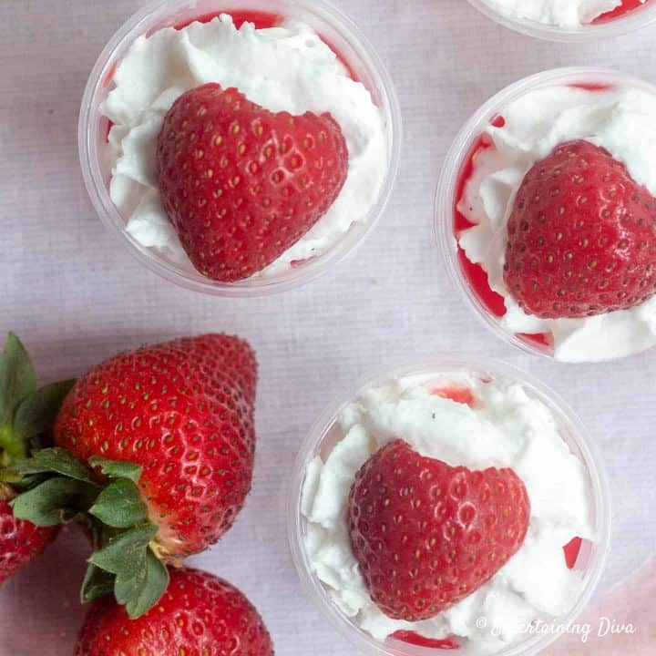 strawberries and whipping cream on top of strawberry shortcake jello shots