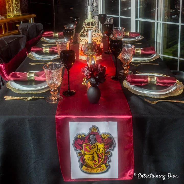 Red and gold Gryffindor table setting with printable crest pinned to the front of the red table runner