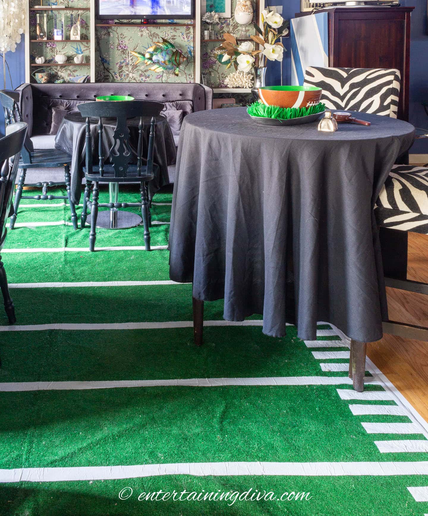 DIY football field area rug in a living room with multiple tables covered with black tablecloths and football decor