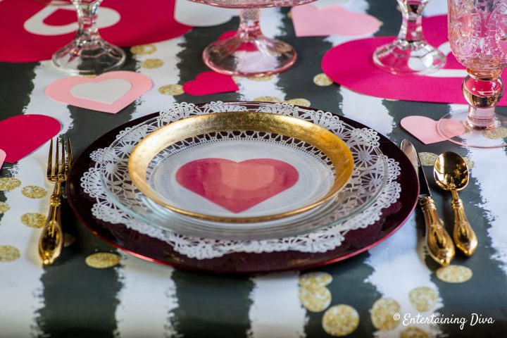 Valentine place setting with gold rimmed clear glass plate on a red charger plate