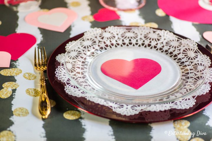 Red heart with white lace doily on a red charger as a Valentine table place setting