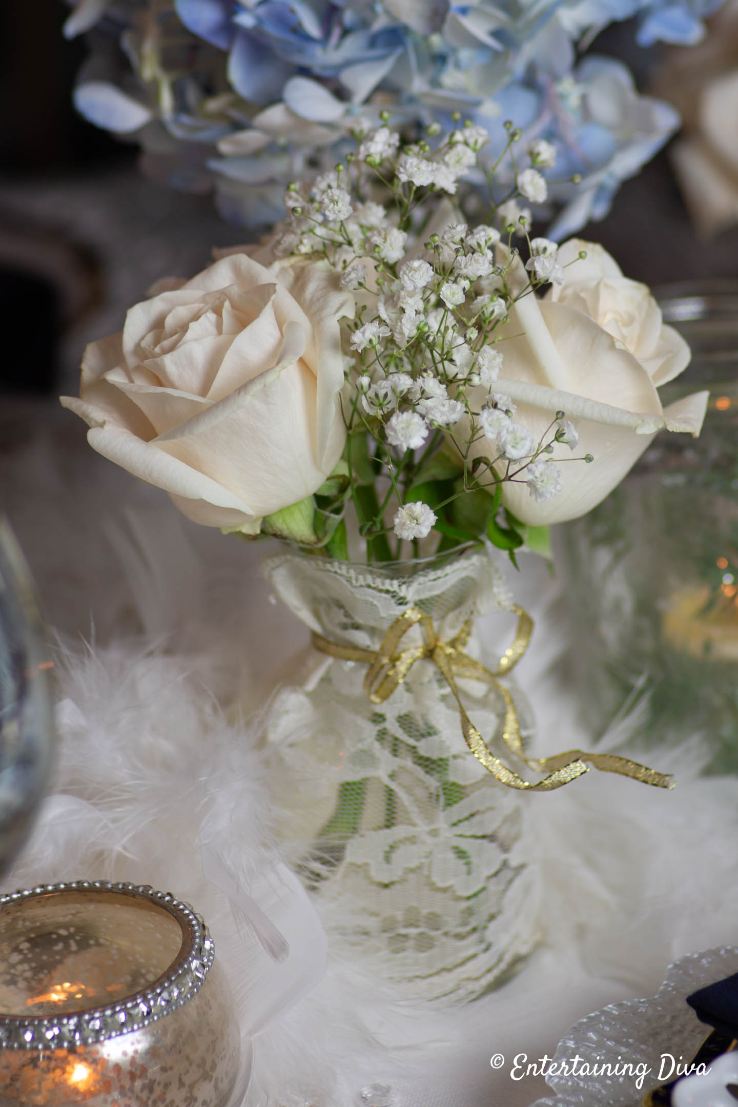 White roses and babies breath in a bud vase as part of a winter wonderland centerpiece