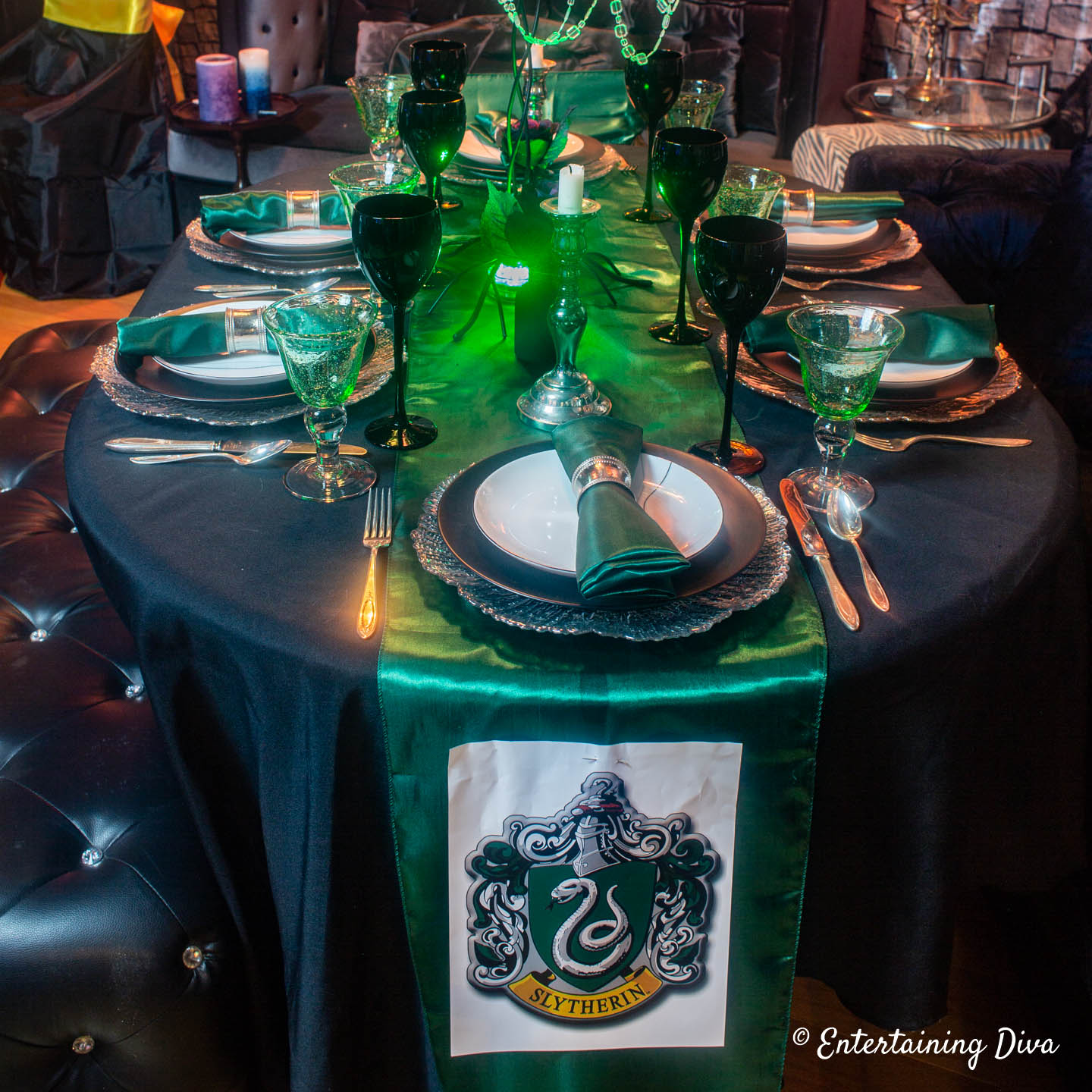 Green, silver and black table setting with a Slytherin house crest on a green table runner