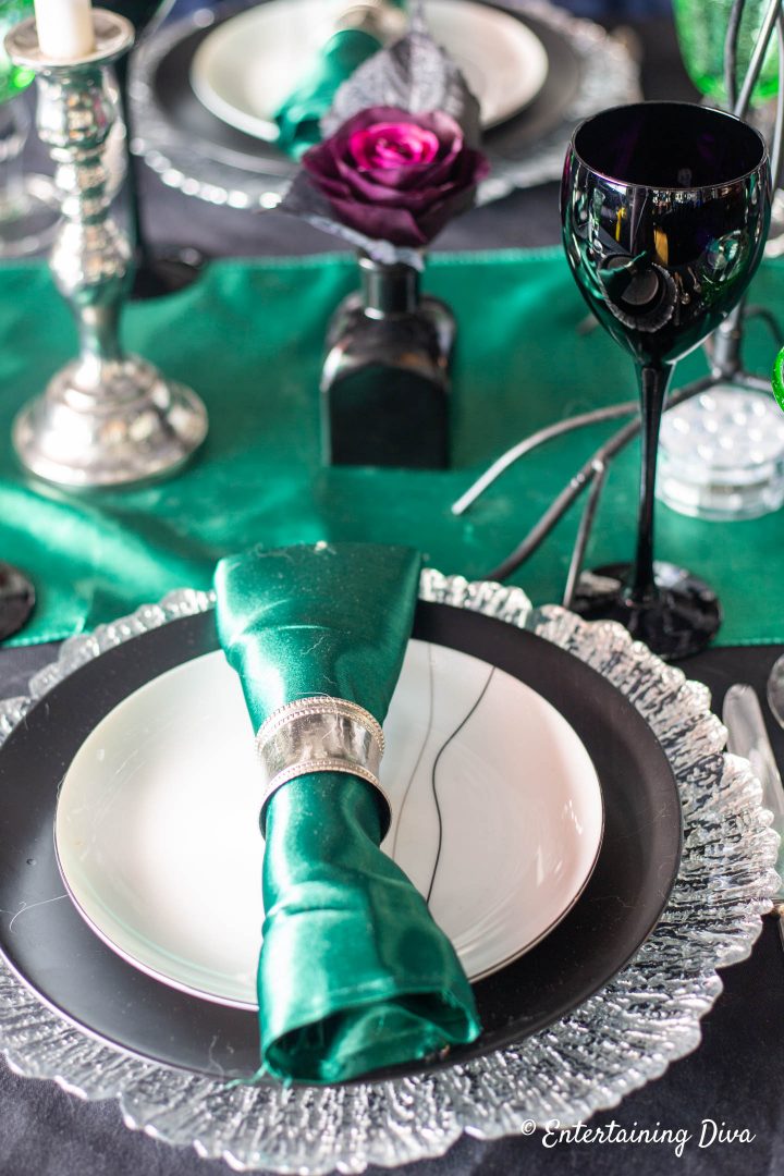Green napkin with a silver napkin ring on black and white plates