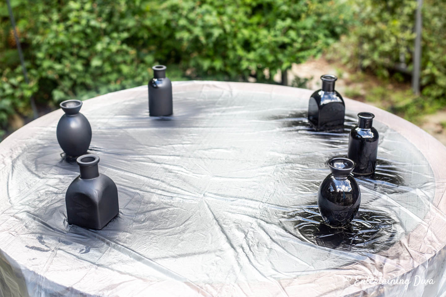 Small glass vases that have been spray painted with chalkboard paint and black lacquer