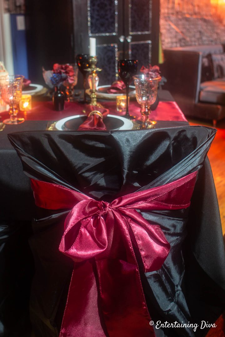 Black chair cover with red chair sash for Gryffindor table decor at a Harry Potter party