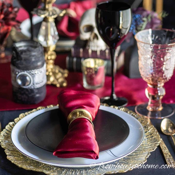 Halloween table setting with black plates, red table runner and gold charger 