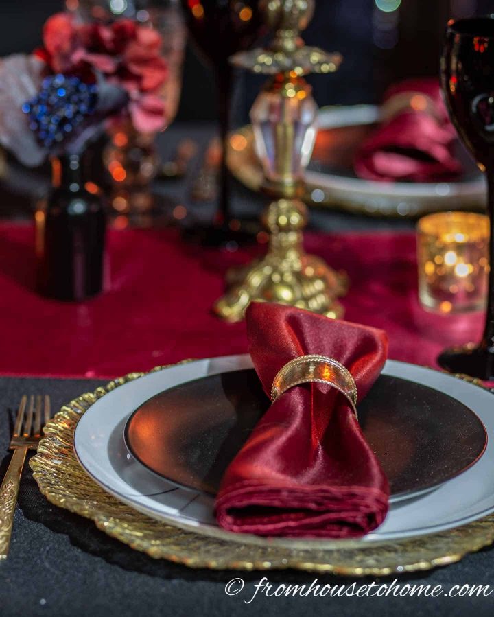 Red napkin on black and white plates over a gold charger