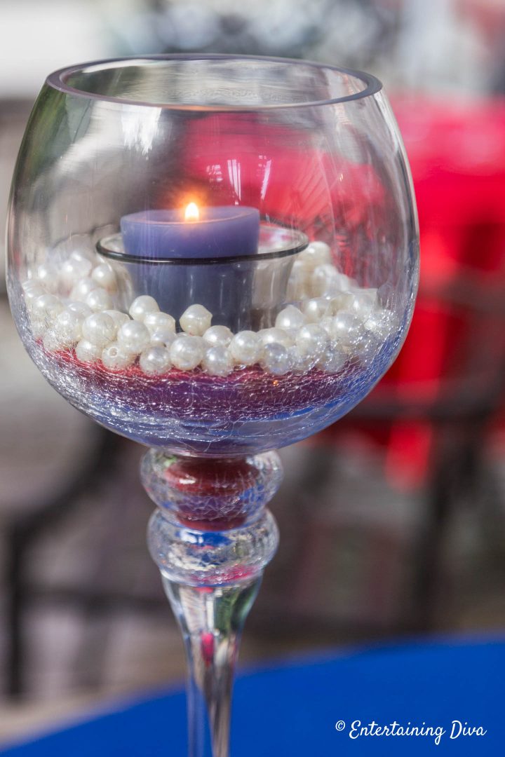 DIY pearl and sand candle holder made with red sand, white pearls and a blue candle