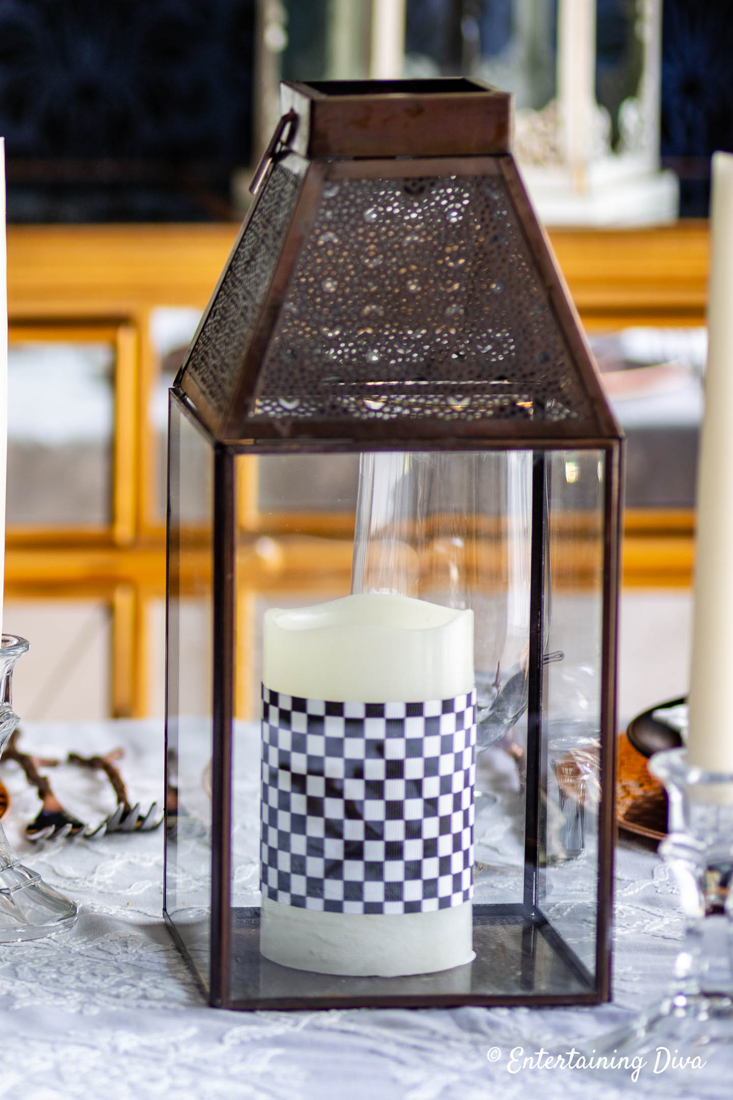 Pillar candles wrapped with black and white checkered ribbon in a lantern