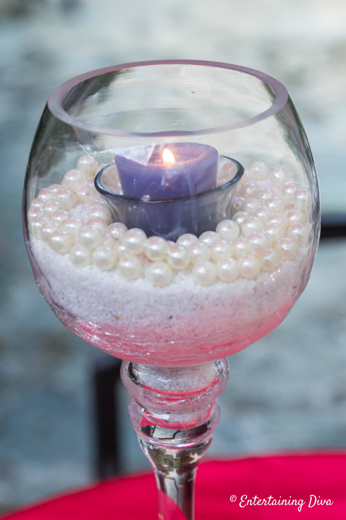 Blue candle in sand and faux pearls used as a centerpiece